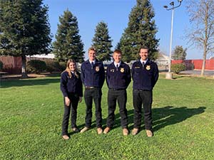 Four FFA students posing in grass field