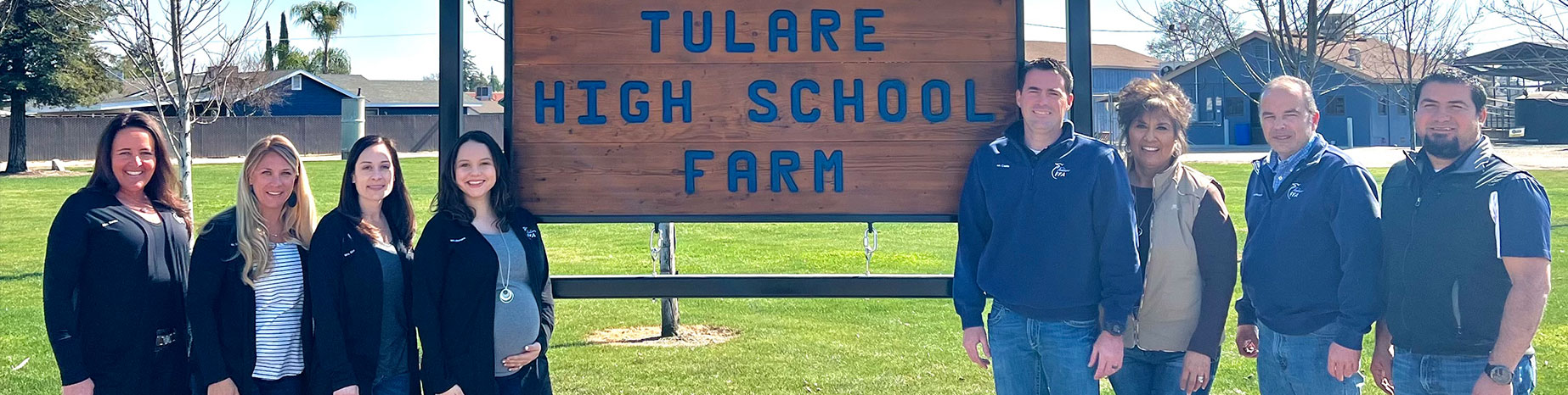 Staff members standing next to Tulare High School Farm sign