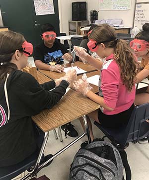 Students working on group project wearing safety goggles