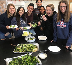students posing with cooked broccoli